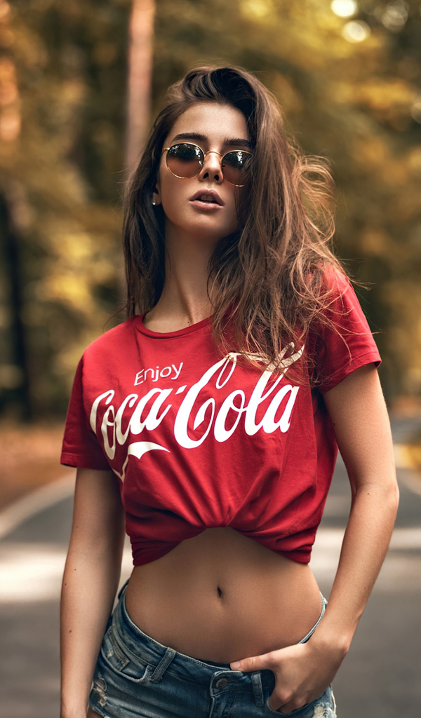 Красивая стройная девушка в футболке кока кола