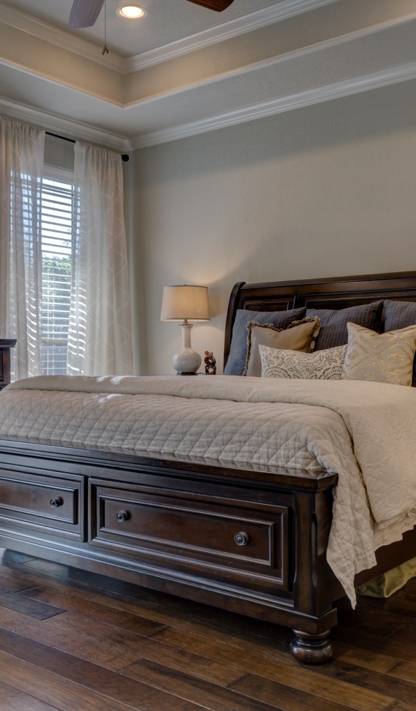 Дорогая деревянная кровать в спальной комнате