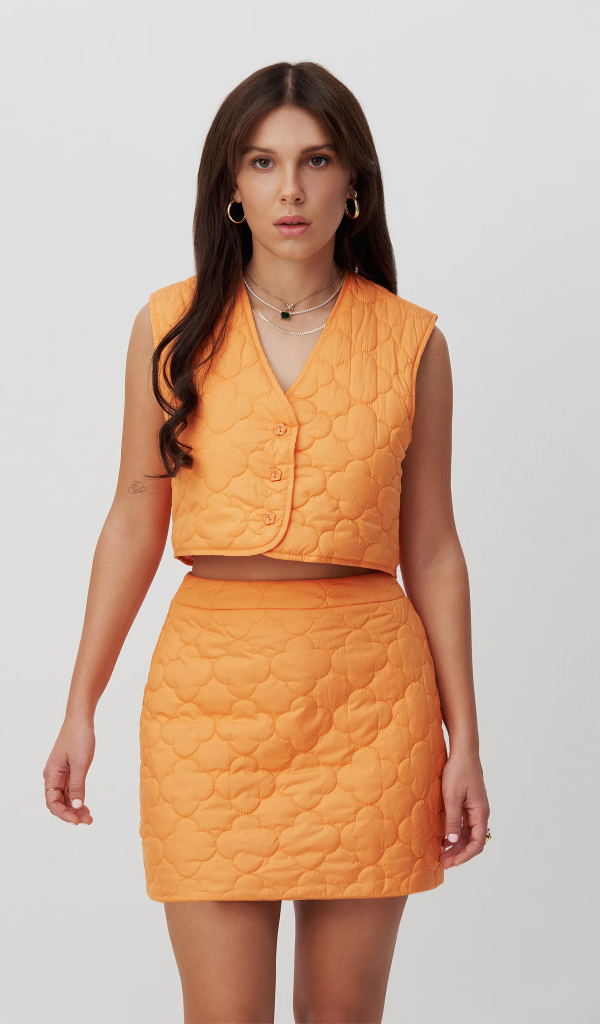 Девушка актриса Милли Бобби Браун в костюме на сером фоне