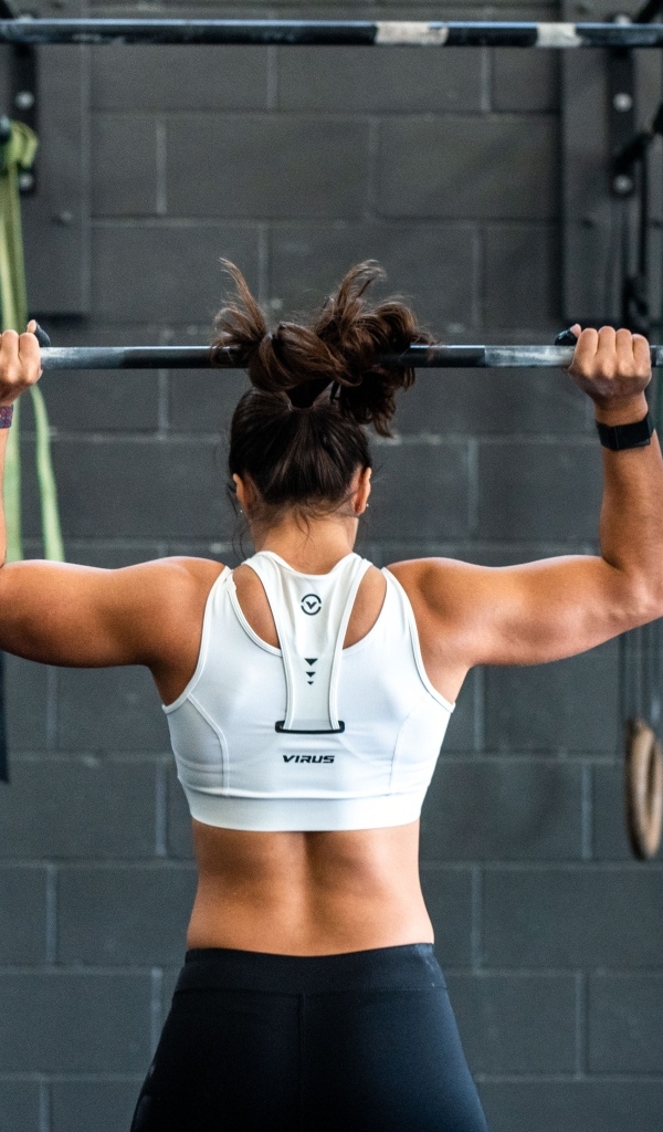 Девушка спортсменка качает штангу
