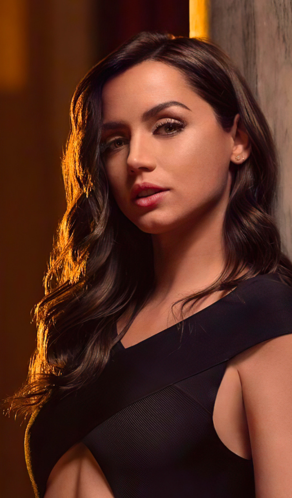 Длинноволосая актриса Ана де Армас стоит у стены