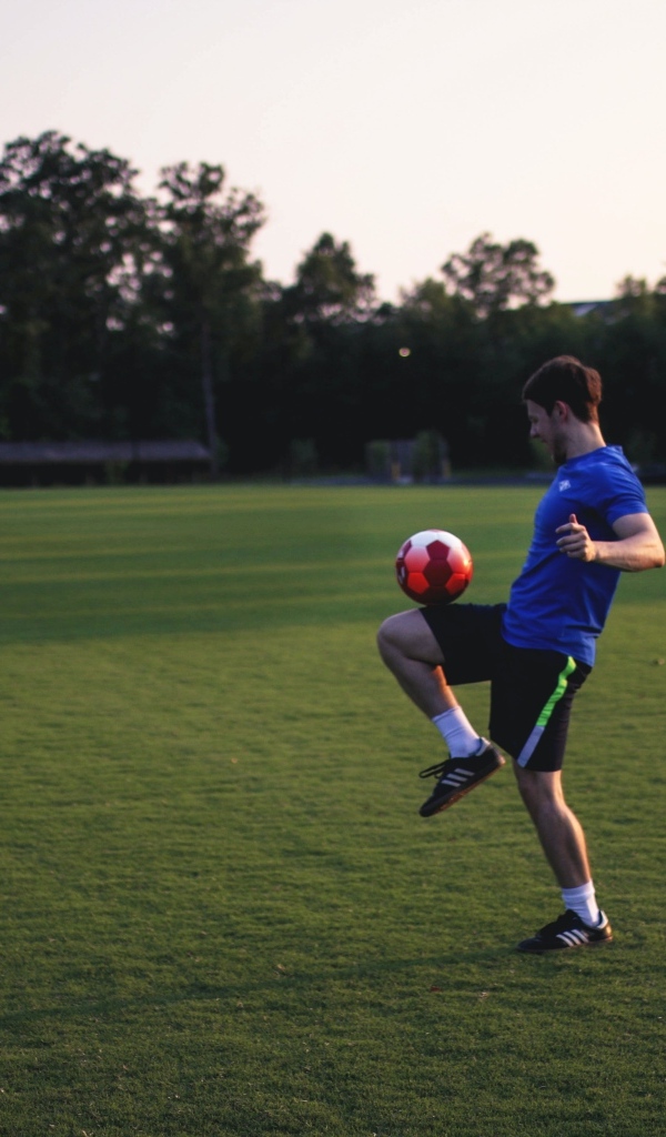 Мужчина футболист с мячом на поле