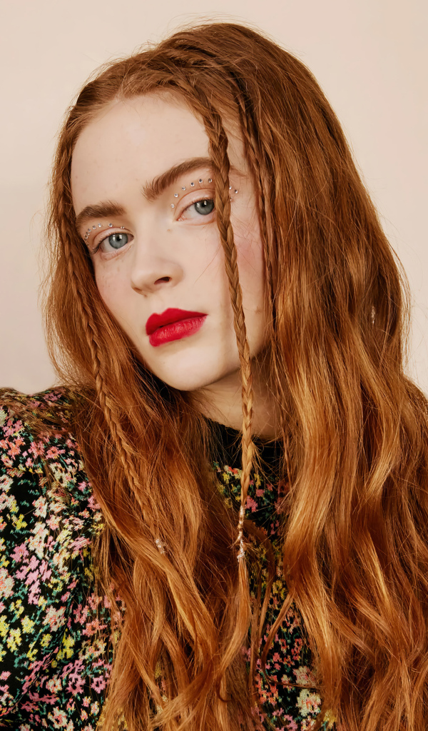 Red-haired Sadie Sink on a pink background