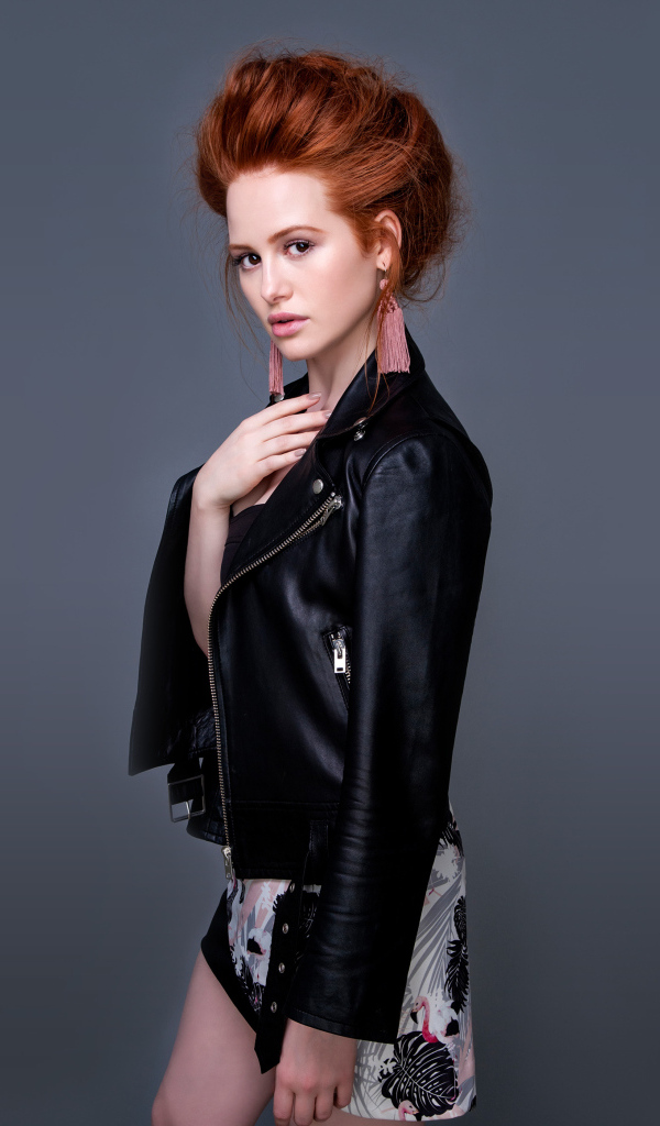 Рыжеволосая актриса Мэделин Петш в черной куртке на сером фоне