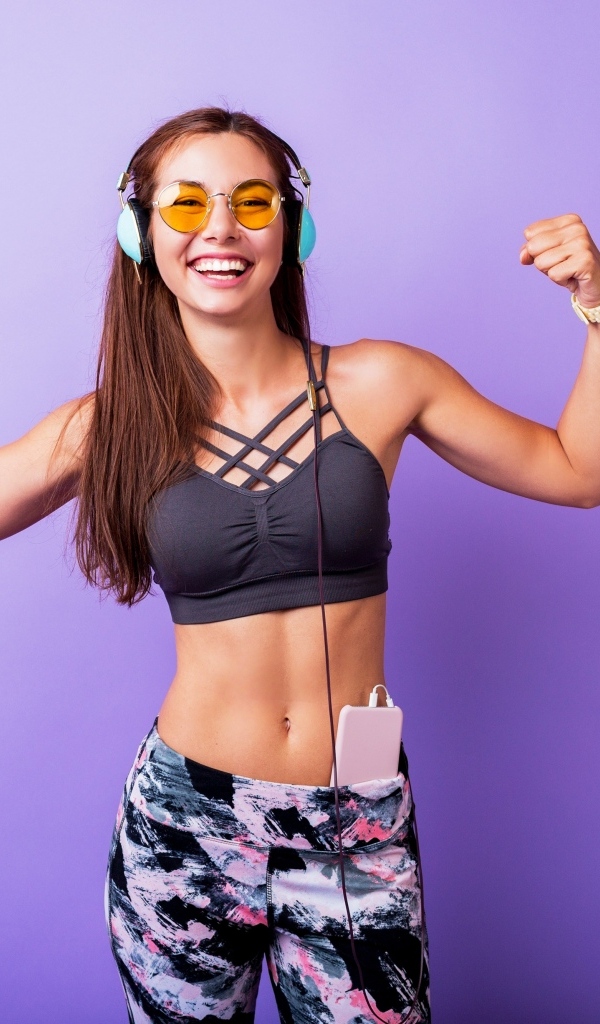 Улыбающаяся спортивная девушка слушает музыку