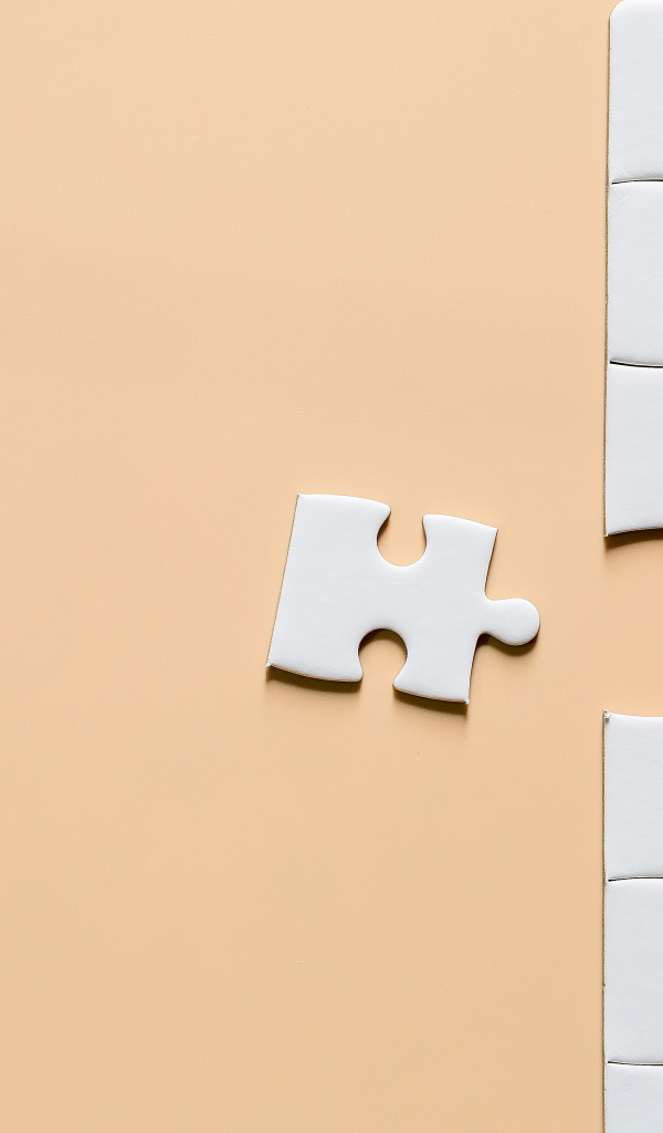 Белый пазл собирают на бежевом фоне
