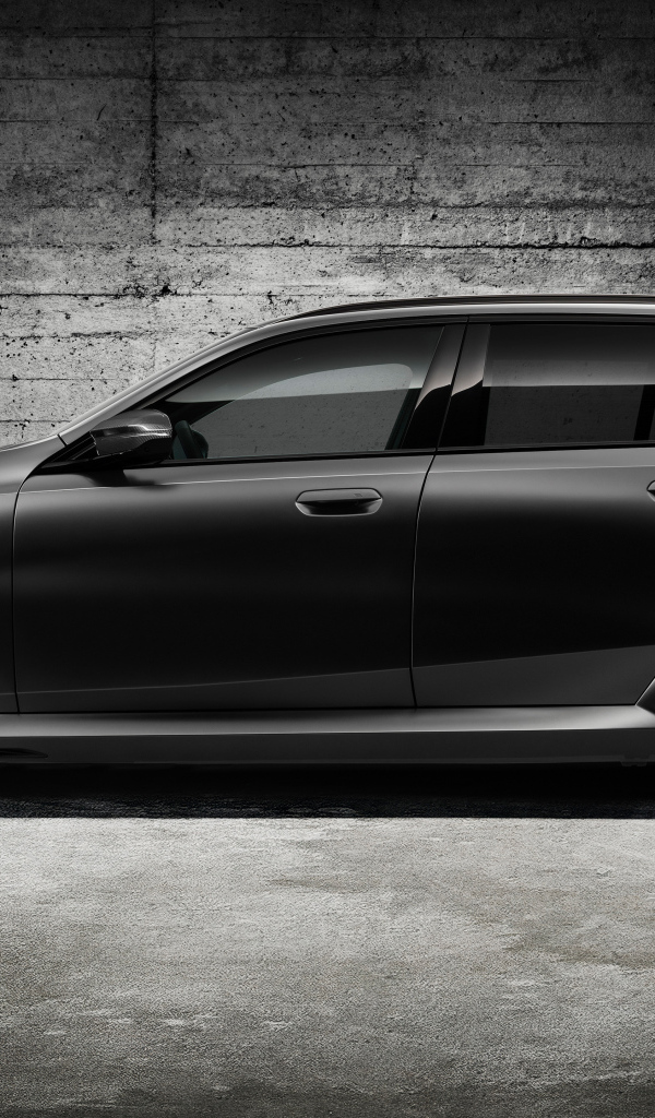 Вид сбоку на черный автомобиль BMW M5 Touring 2024 года
