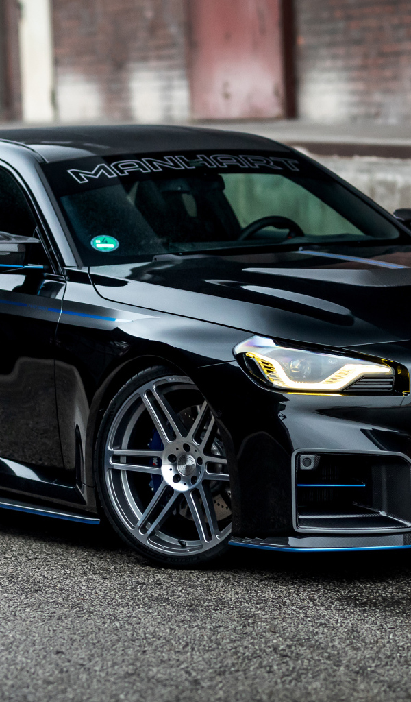 Черный автомобиль BMW M2 Manhart MH2 560 на сером фоне в городе