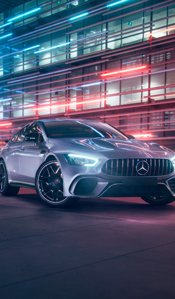 Серебристый автомобиль Mercedes AMG GT4 на фоне здания