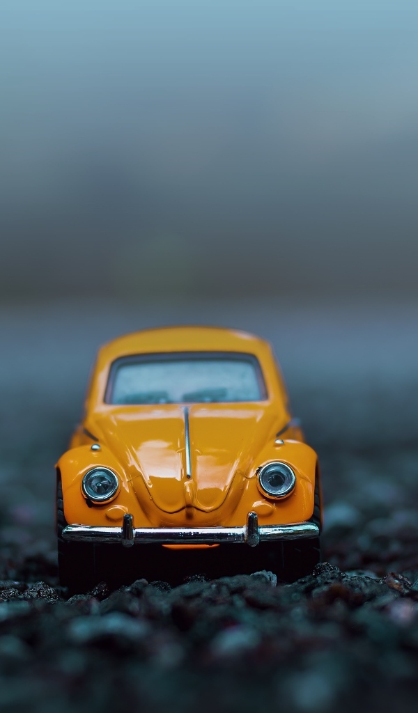 Маленькая игрушечная машинка стоит на асфальте