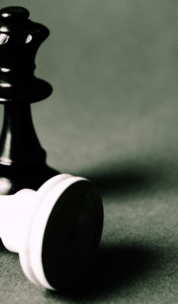 Черная и белая шахматные фигуры на сером столе