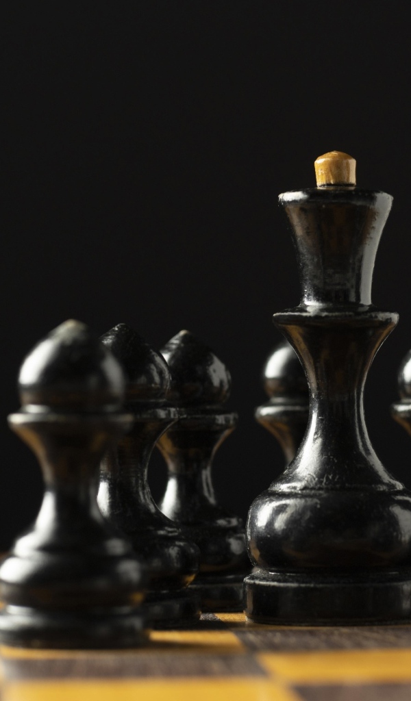 Черные шахматные фигуры на доске на черном фоне