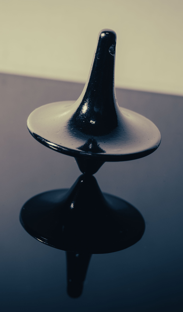 Черный волчок на ровной поверхности