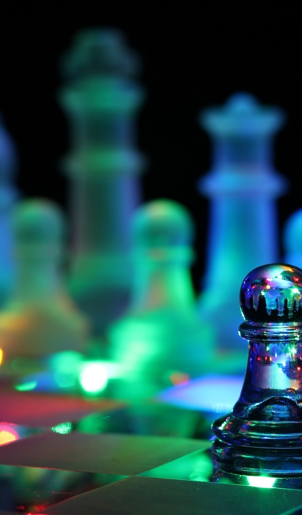 Стеклянные шахматы с гирляндой лежат на доске