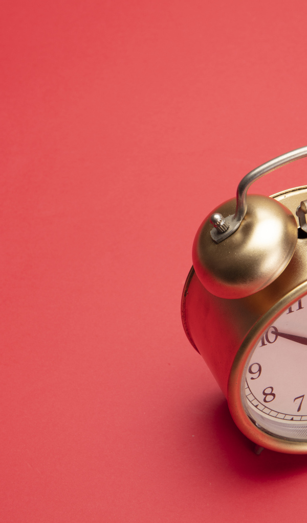 Золотой будильник на красном фоне