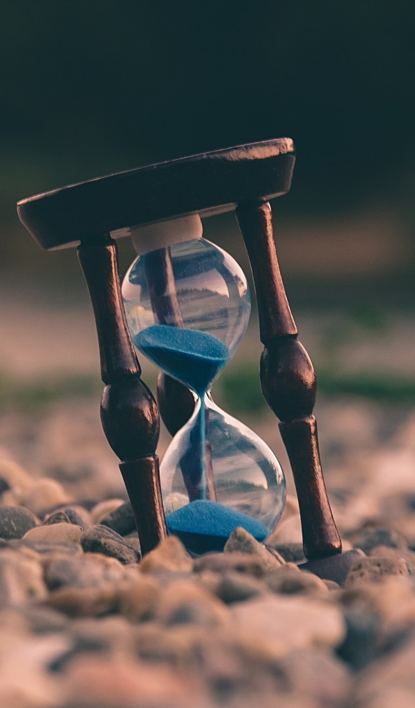 Песочные часы лежат на мелких камнях
