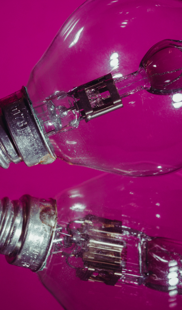 Лампочка отражается в поверхности на сиреневом фоне