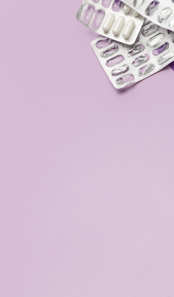 Таблетки, стетоскоп и будильник на сиреневом фоне