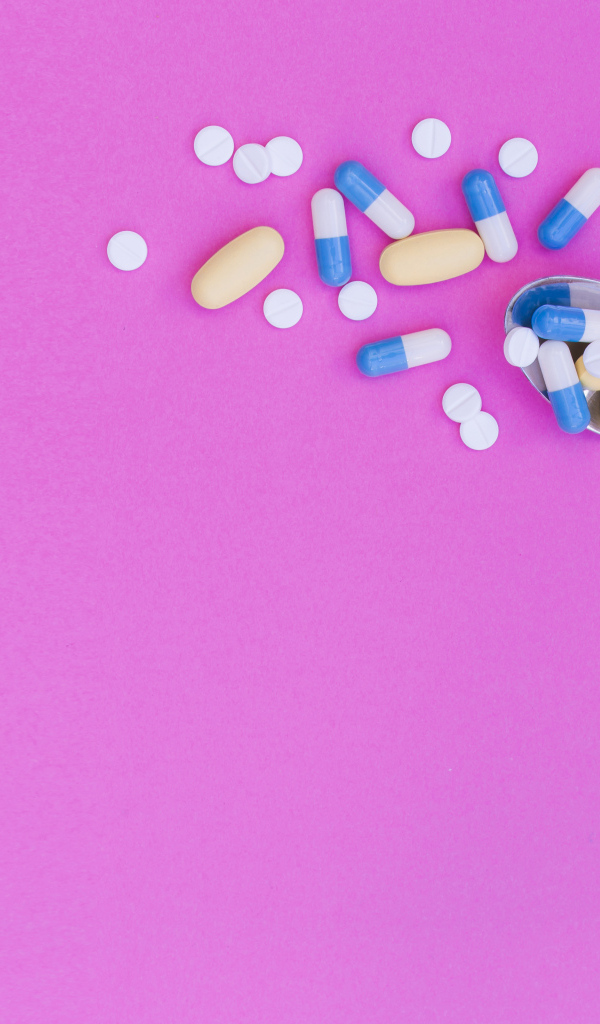 Таблетки с ложкой на розовом фоне