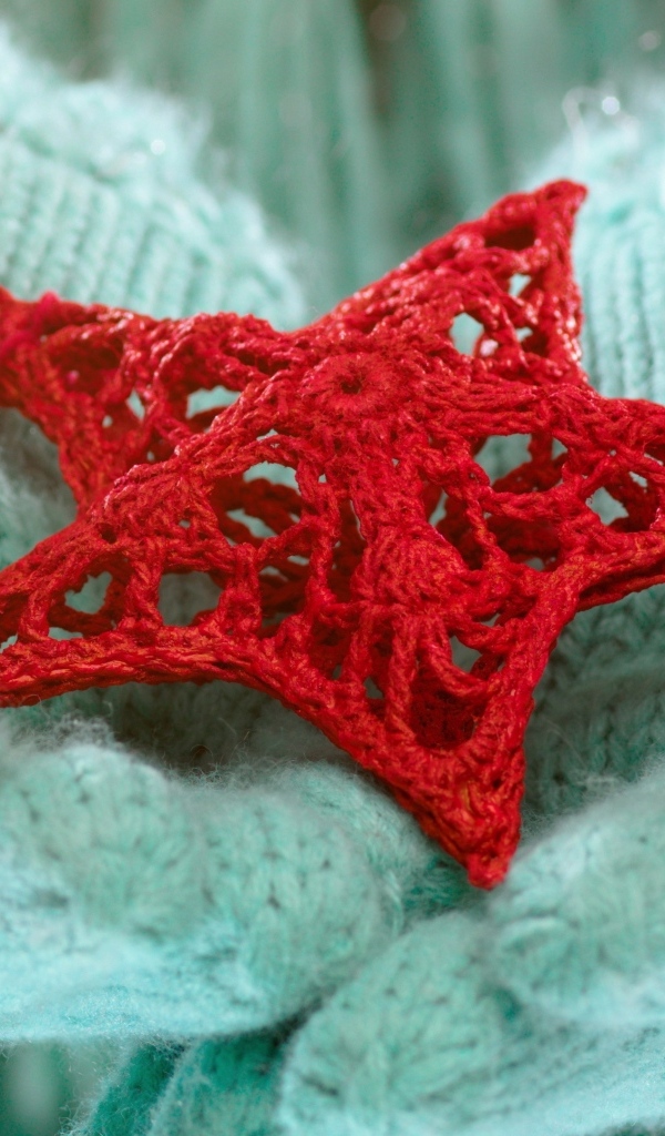 Красная вязаная звезда в руках в варежках