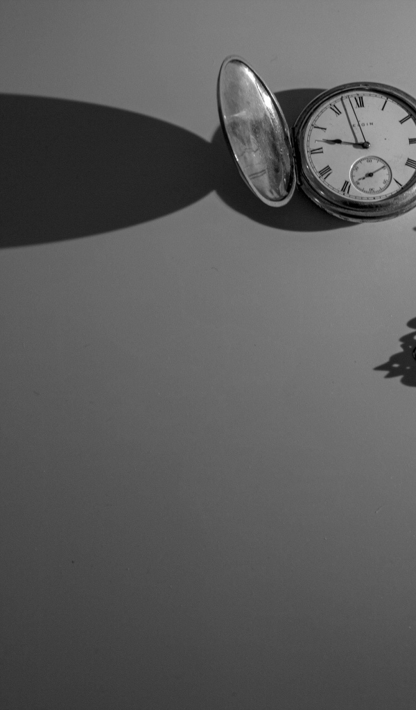 Тень от карманных часов на сером фоне