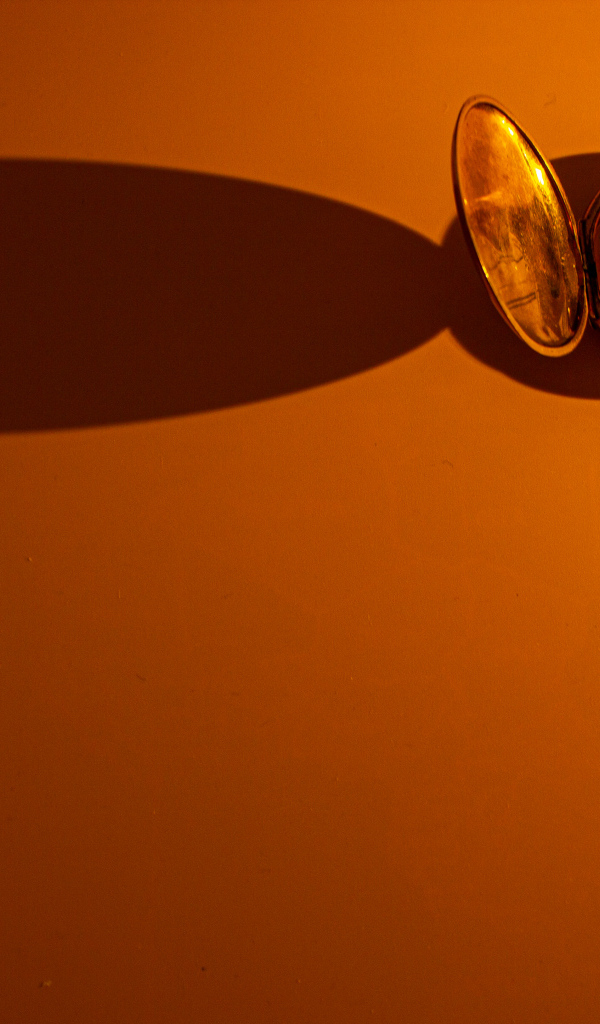 Тень от карманных часов на оранжевом фоне