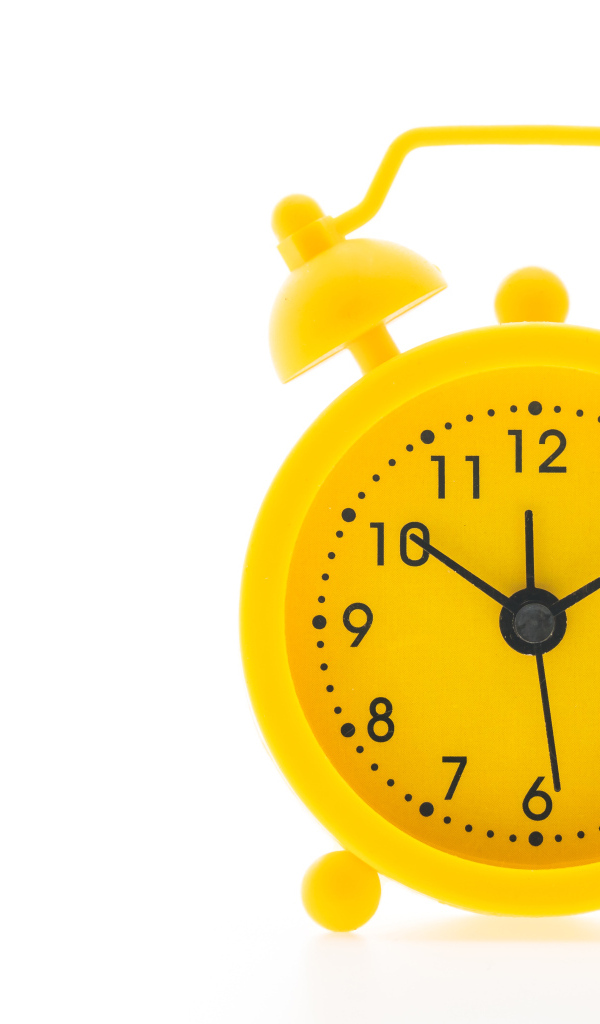 Желтый будильник на белом фоне
