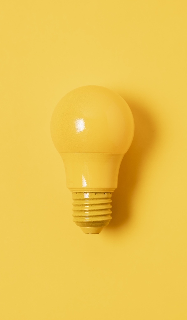 Желтая лампочка накаливания на желтом фоне
