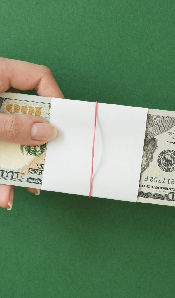 Пачка денег в руке у девушки на зеленом фоне