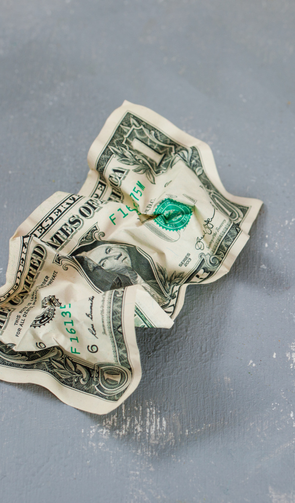 Смятая купюра один доллар на сером столе