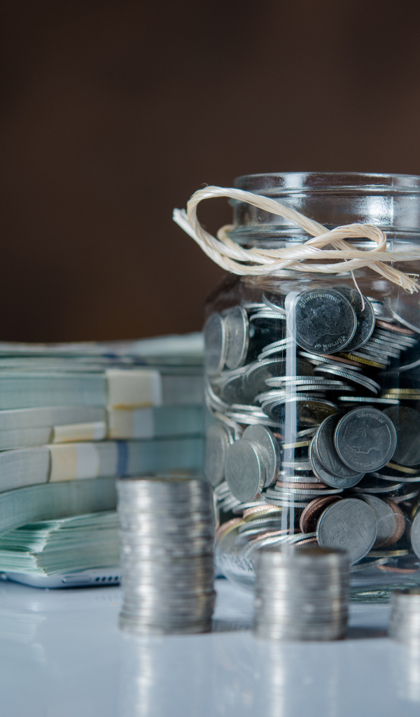 Банка с монетами на столе с пачками денег