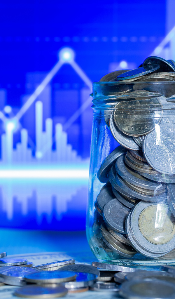 Банка с монетами на фоне таблицы