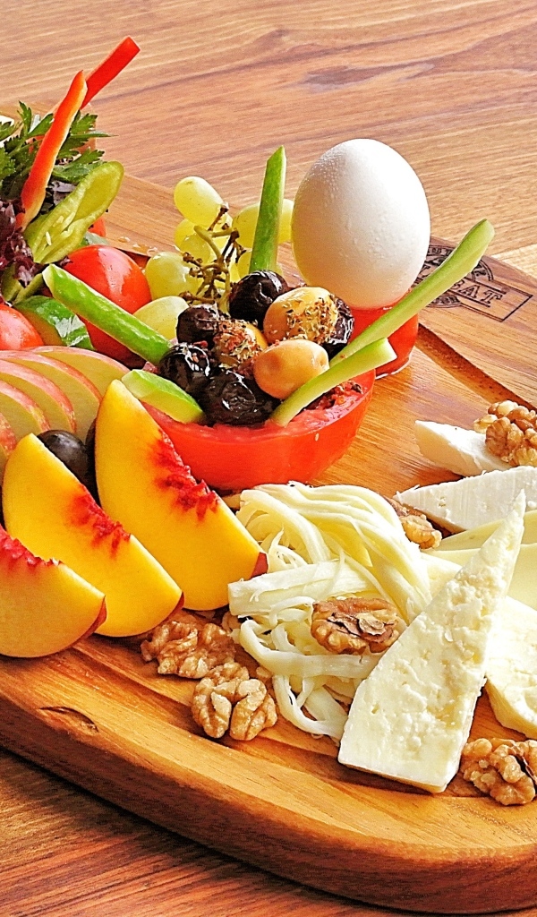 Сыр на доске с фруктами и салатом