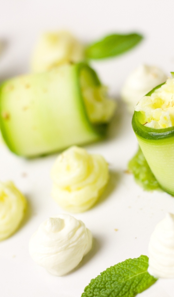 Рулетики из огурца с кремом на белом фоне