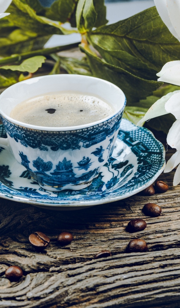 Чашка кофе с макарунами на столе с цветами