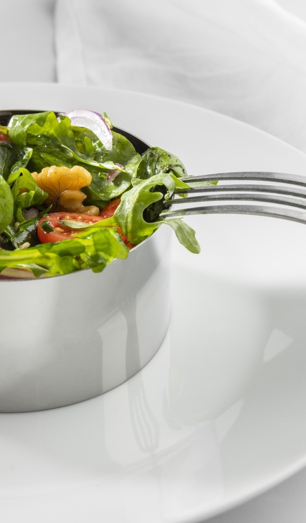 Зеленый салат с орехами на большой белой тарелке