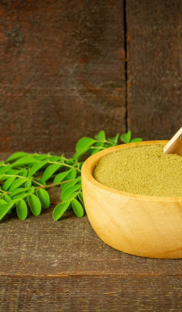Порошок моринга на столе с листьями