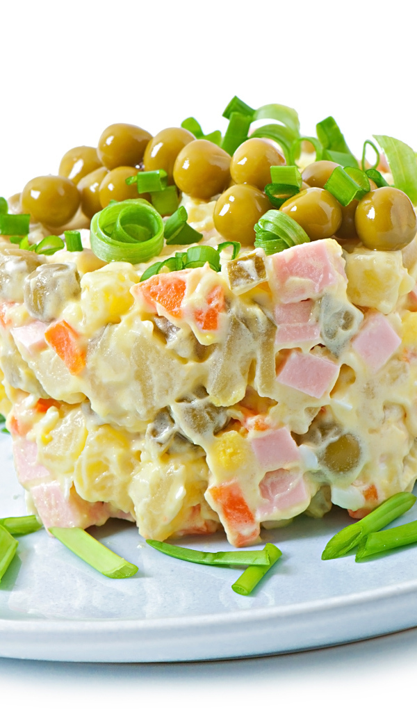 Салат оливье с зеленым горошком на тарелке 