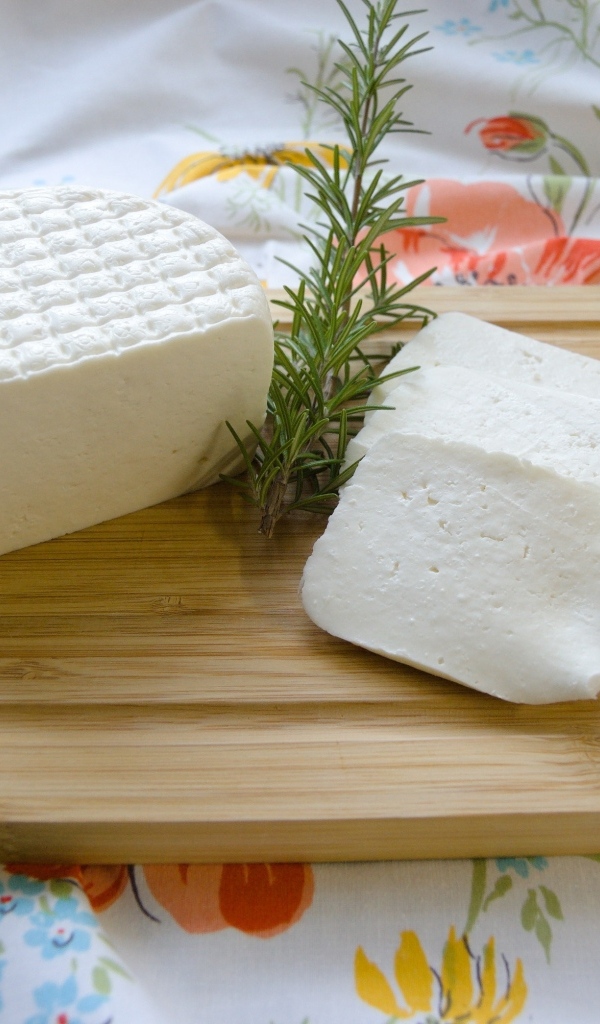 Кусок сыра с розмарином на разделочной доске
