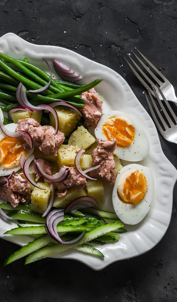 Картофель с мясом, яйцами, спаржей и огурцами на тарелке