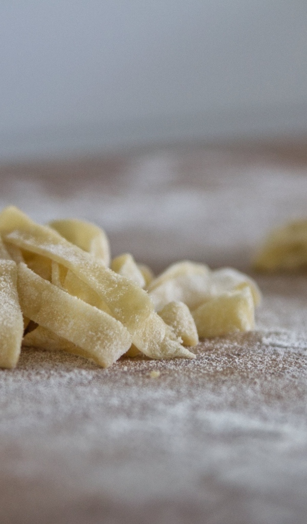 Сырое тесто для лапши на покрытом мукой столе