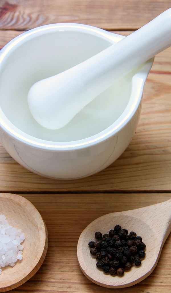 Соль с перцем на столе с деревянной ступкой