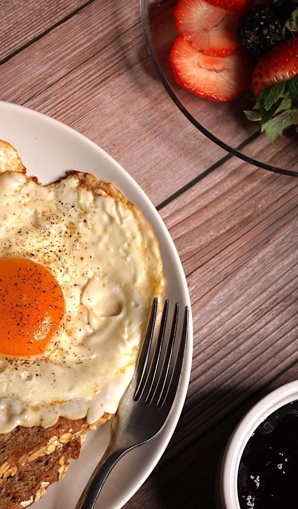 Яичница с гренками на столе с клубникой