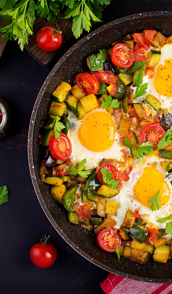 Яичница с овощами в сковороде на столе