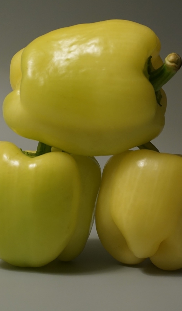 Три желтых перца на сером фоне