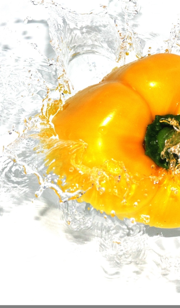 Желтый сладкий перец в воде на белом фоне