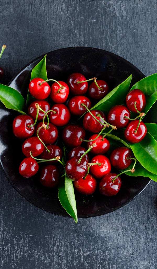 Черная  тарелка с красными ягодами черешни