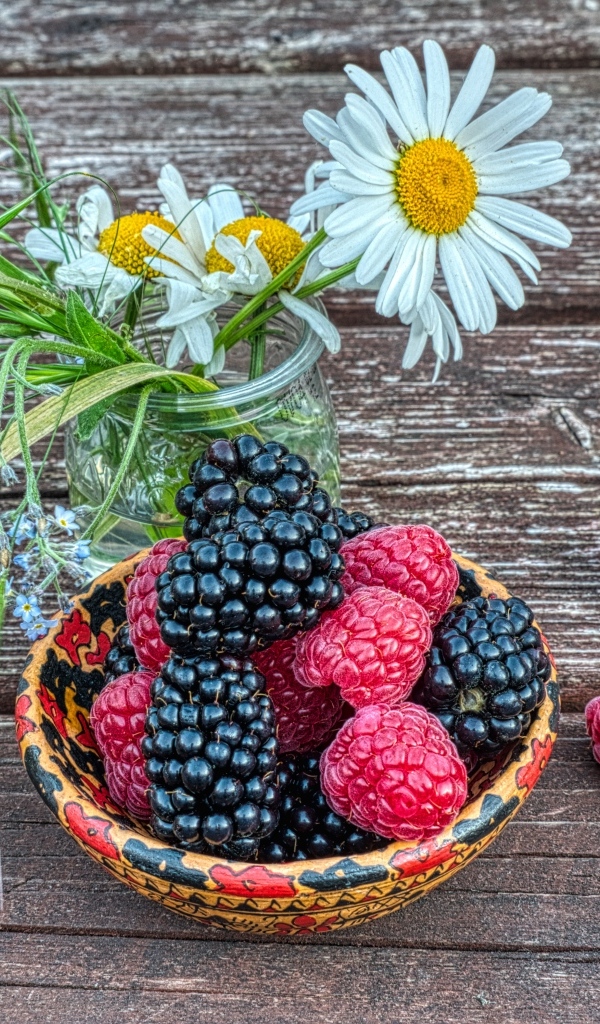 Ягоды черники и малины на столе с ромашками