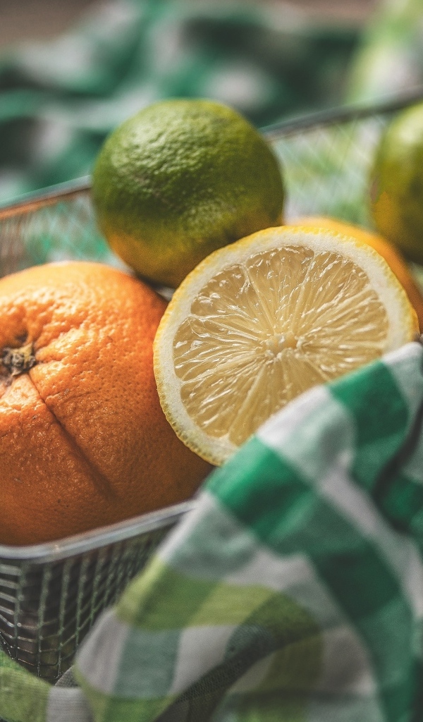 Цитрусовые фрукты в железной корзинке на столе