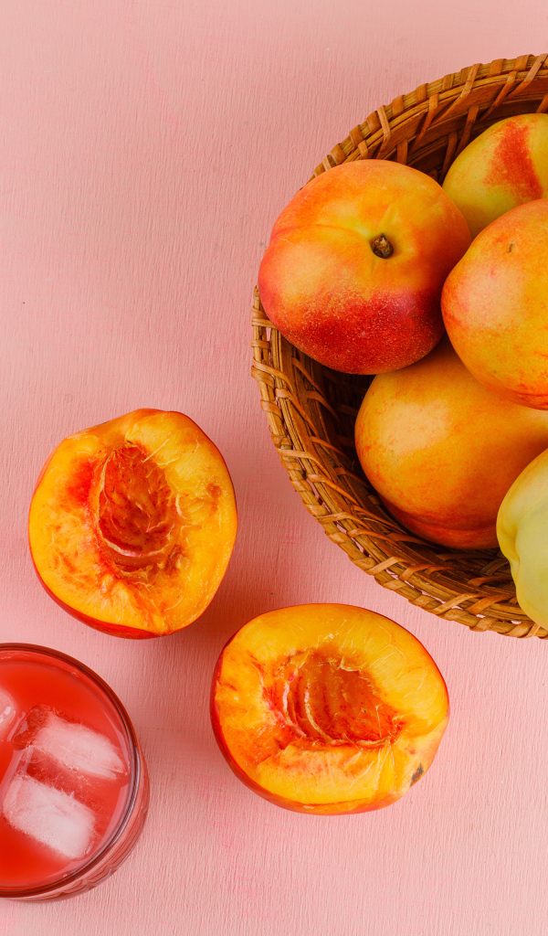 Свежий нектарин в корзине на розовом столе